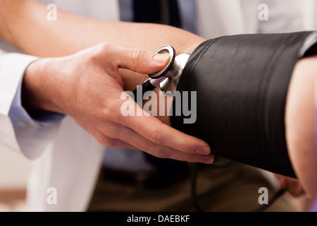 Mid adult doctor using stethoscope and blood pressure cuff on patient, close up Stock Photo