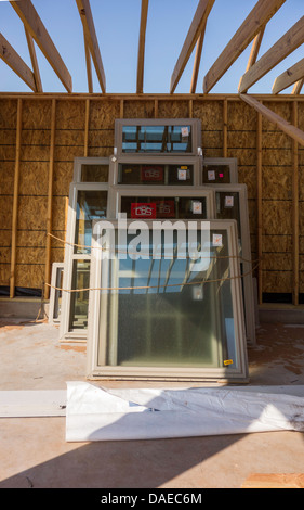 New home  custom construction in rural Oklahoma, USA.  A stack of windows lean against an unfinished wall in the garage area. Stock Photo