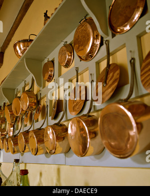Rows of copper pots and pans hanging on wall Stock Photo