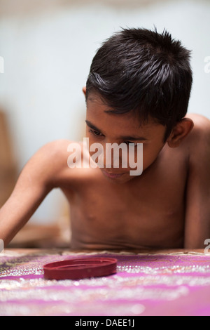 A boy works on making traditional Jamdani saree in Mirpur Benarashi Palli, Dhaka, Bangladesh, a poor Bengali neighborhood. Stock Photo