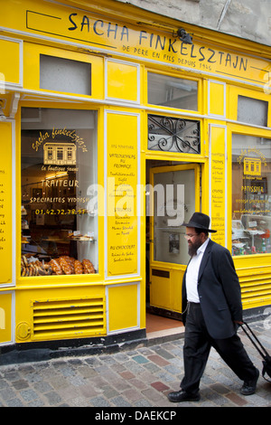 Orthodox Jew walks past historic Yiddish bakery - Finkelsztajn in the Marais, Paris France Stock Photo