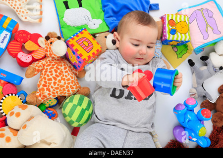 baby lying beween playthings in supine position Stock Photo