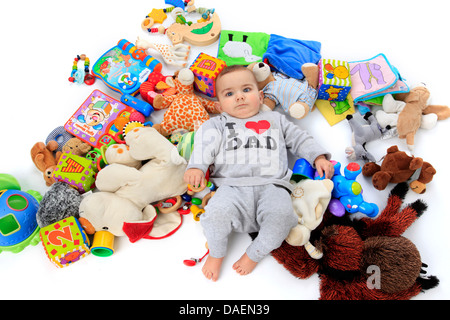 happy baby lying in a heap of toys wearing a pully with the lable 'I love dad' Stock Photo