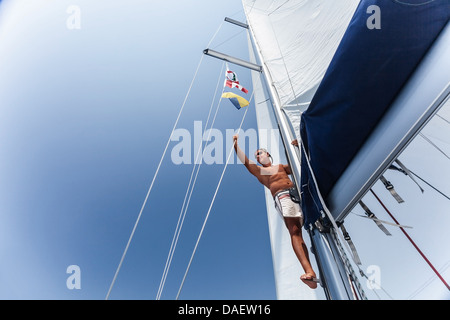Handsome man working on sailing ship, cute sailor fixed sail, young cheerful skipper on the yacht, active lifestyle Stock Photo