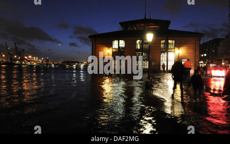 Onlookers walk through the water at the flooded fish market in Hamburg, Germany, 27 November 2011. The stormy weather caused high water in Hamburg. Photo: ANGELIKA WARMUTH Stock Photo