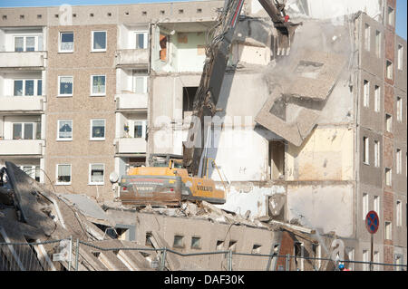 An excavator tears down a GDR highrise in Stralsund, Germany, 28 November 2011. The Stralsund housing association starts to deconstruct its apartment blocks. The federal government funds the demolition of 64 units as part of the 'Urban Redevelopment East' development programme. The block seen in the picture will be auctioned. The block from 1978 belongs to the federal government an Stock Photo