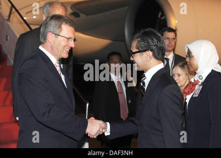 German President Christian Wulff (L) receives a flower lei and is welcomed by Indinesian Foreign Minister Marty Natalegawa upon his arrival at the airport in Jakarta, Indonesia, 30 November 2011. Wulff visits Bangladesh and Indonesia during his six-day visit to Asia. Photo: RAINER JENSEN Stock Photo