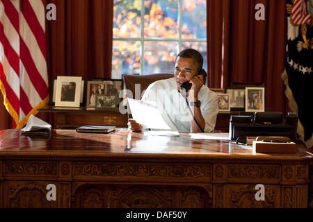 United States President Barack Obama makes Thanksgiving Day phone calls from the Oval Office of the White House in Washington, DC. In all he phoned 10 members of U.S. armed services - two from each the Army, Air Force, Coast Guard, Marine Corps, and Navy - deployed in support of Operation New Dawn and Operation Enduring Freedom. The President thanked each of them for their service  Stock Photo