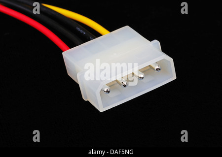 Four pin peripheral power connector from PSU in tower PC against a black background. Stock Photo