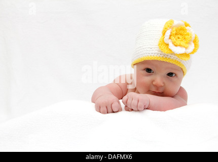 Baby with a knitted white hat baby on stomach Stock Photo