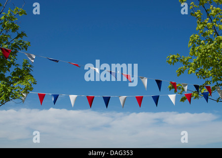 Flag bunting (red, white and blue) with a blue sky and clouds behind. Stock Photo