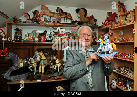 Rocking horse collector Guenther Tlotzek stands amidst his private museum collection of rocking horses and holds a music box in Nettetal, Germany, 16 March 2011. The 88 years old holds the world's largest collection of rocking horses. Photo: Horst Ossinger Stock Photo