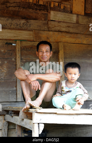 Happy dad carries serious podgy cute son. Stock Photo