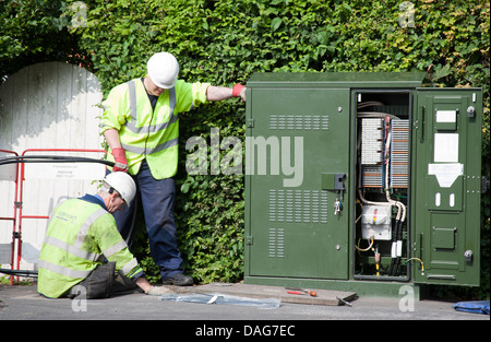 A BT Openreach telecommunications technician working in a manhole at the roadside, Southport, Merseyside, UK Stock Photo