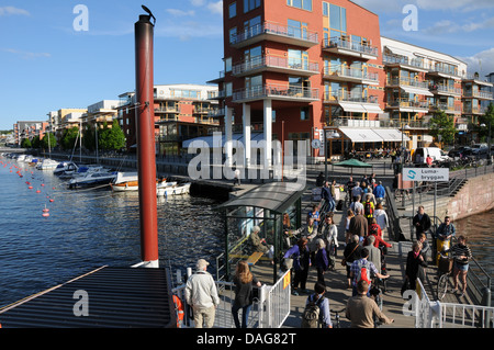 Sustainable city development at  Hammarby Sjöstad in Stockholm with waterfront restaurants, boat docks, apartments and ferryboat Stock Photo