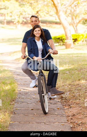 cheerful teen couple riding a bike outdoors Stock Photo