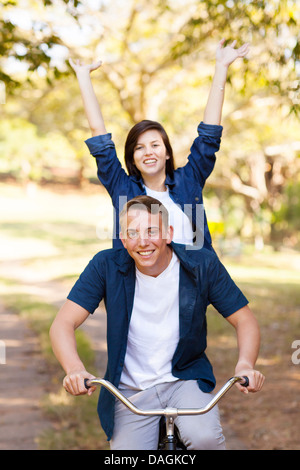cheerful teenage girl having fun riding a bicycle with boyfriend Stock Photo