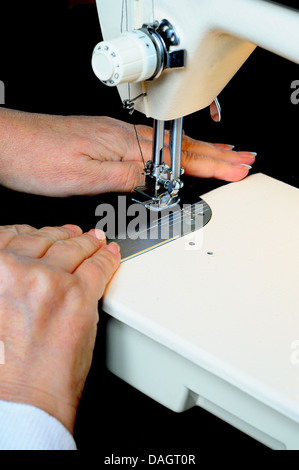 Woman using a domestic electric sewing machine to stitch black velvet, England, UK, Western Europe. Stock Photo