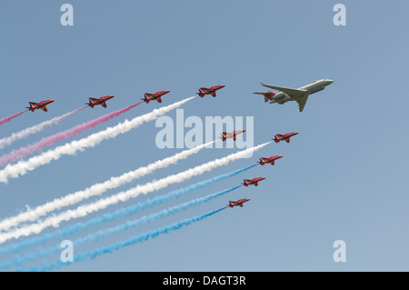 The British Royal Air Force Red Arrows Military Aerobatic Display Team make a rare formation flypast with a Bombardier Sentinel Stock Photo