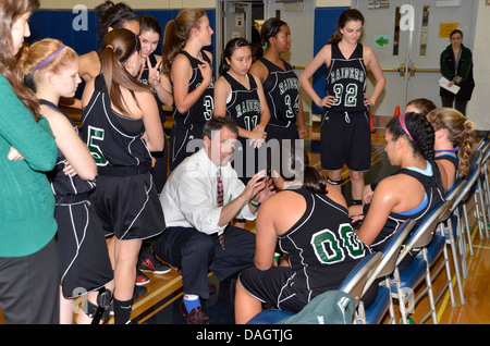 Coach discusses strategy with his team at the high school basketball game Stock Photo