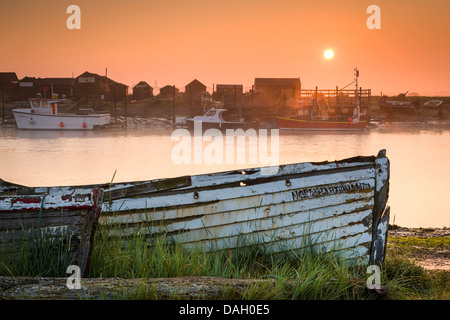 The sun rises over two long forgotten boats on the shore of the river Blyth estuary in Walberswick, Suffolk - England. Stock Photo