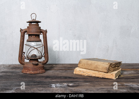 rustic oil lamp on wooden table and old books Stock Photo