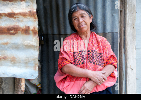 Mayan woman in traditional clothing standing in front of her shack. Nahuala, Solola, Guatemala, Central America. credit: Kraig Lieb Stock Photo