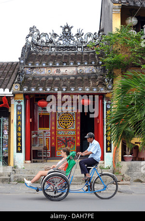 Vietnamese rickshaw driver and passenger. Hoi An, Vietnam. Tourism Stock Photo