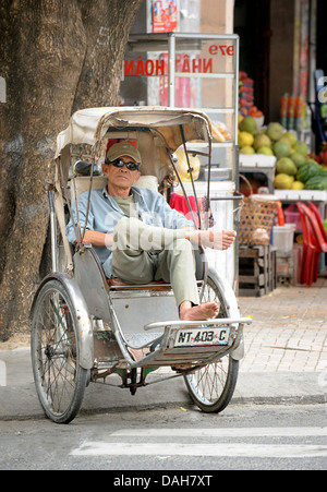 Cyclo rickshaw driver on his rickshaw, resting, Nha Trang, Vietnam Stock Photo