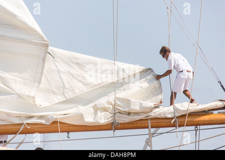 A deck hand rigs the sails on the 196-foot sailing yacht Germania Nova as it sails Charleston Harbor June 26, 2013 in Charleston, South Carolina. Stock Photo