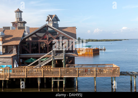 Quaint Seabreeze waterfront stilt restaurant along Dock Street in Cedar Key, Florida. A tour boat with tourists visible beyond. Stock Photo