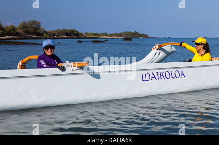 Women hold outrigger canoe in Anaehoomalu Bay in Waikoloa on the Big Island of Hawaii before paddling adventure Stock Photo