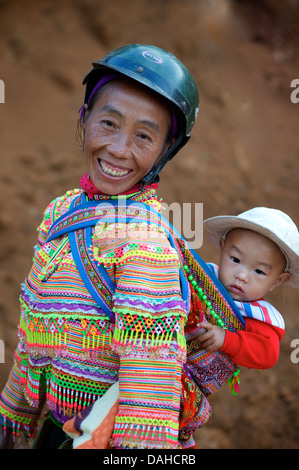 Flower Hmong woman with child  in distinctive tribal costume. Can Cau, Near Bac Ha.  Vietnam. Model released Stock Photo