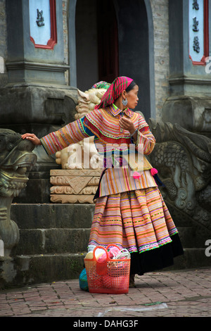 Flower Hmong woman in distinctive tribal costume at temple steps, Bac Ha, Vietnam Stock Photo