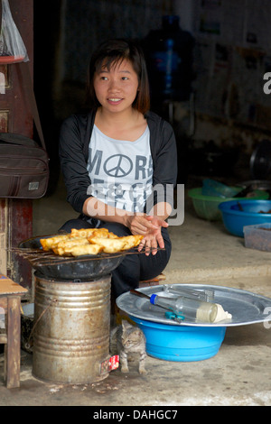 Young Vietnamese woman frying homemade snacks outside her home, Bac Ha, Vietnam Stock Photo