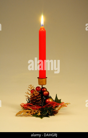 Red candle in a Christmas holder against a plain background. Stock Photo