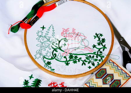 White tablecloth in a round frame being embroidered with Christmas scene. Stock Photo