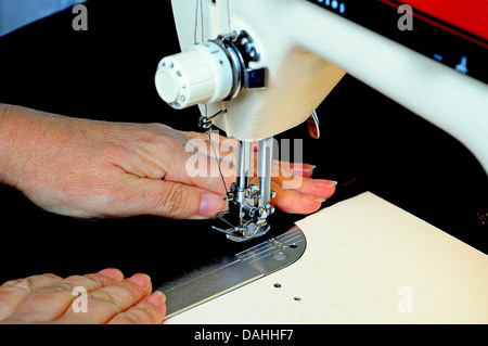 Woman using a domestic electric sewing machine to stitch black velvet. Stock Photo