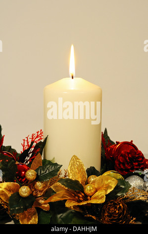 White candle and Christmas flowers against a white background. Stock Photo