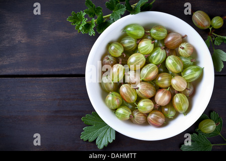 Green gooseberries in bowl on table background with copy space. Top view Stock Photo