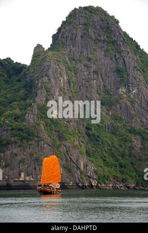 Halong Bay, Vietnam. Vietnamese man fishing from boat and traditional style 'junk' Stock Photo