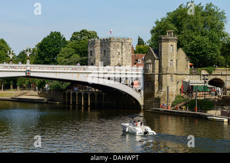 A small pleasure boat on the River Ouse passes under Lendal Bridge in York city centre UK Stock Photo