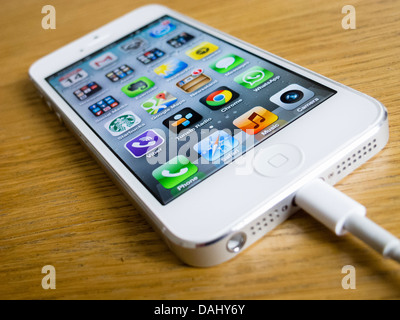 Detail of  white iPhone 5 smartphone with charger attached Stock Photo