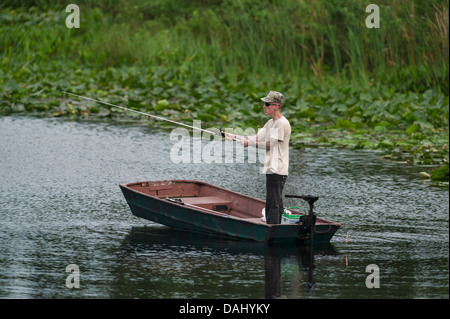 A thin man standing and fishing from a small row boat on the Haines Creek River in Lake County Leesburg, Florida USA Stock Photo