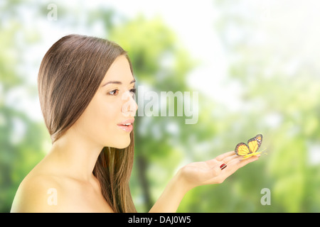 Beautiful young female holding a butterfly and posing in a park Stock Photo