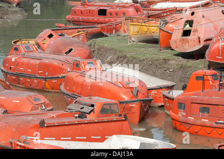 Old discarded bright orange life boats from ships for sale close to the ship breaking yards of Sitakunda,  Chittagong Bangladesh Stock Photo