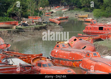 Old discarded bright orange life boats from ships for sale close to the ship breaking yards of Sitakunda,  Chittagong Bangladesh Stock Photo