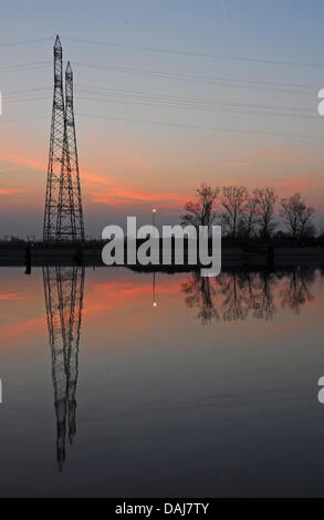Power lines next to the nuclear power plant Fessenheim are reflected in the water of the Rhine river during sunset, France, 23 March 2011. German and French environmentalists demand the shutdown of the power plant. Photo: Patrick Seeger Stock Photo