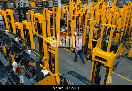 (dpa File) - An archive picture, dated 14 April 2004, shows a member of staff of forklift manufacturer Jungheinrich AG walking pass rows of forklift trucks at the assembly plant in Hamburg, Germany. Photo: Ulrich Perrey Stock Photo