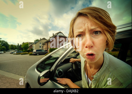 Angry woman car driver sticking out her head out of the window Stock Photo